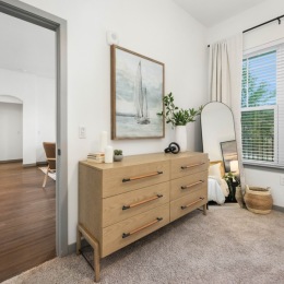a dresser in a bedroom with decor on the walls and a large window