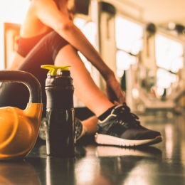 close-up of a person sitting in a fitness center with a water bottle and free weight