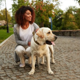 a woman smiling outside with holding a dog